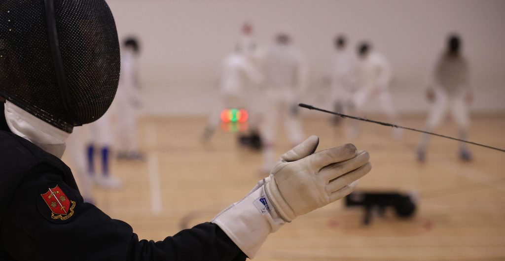 A close up view of a fencing coach extending his arm towards a fencing weapon